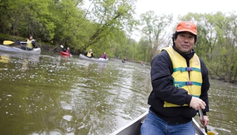 Man on kayak in river with kayaks in the background.