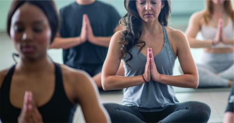 Group of adults in seating pose with prayer hands