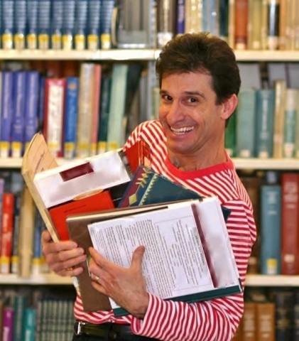 Chris Fascione holding books in front of a bookshelf.