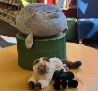 A seal, cat, and dog stuffed animals on a bench.