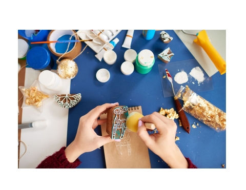 hands creating a craft with stamps and gold glitter.