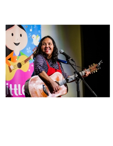 Little Miss Ann with a guitar standing in front of a microphone.